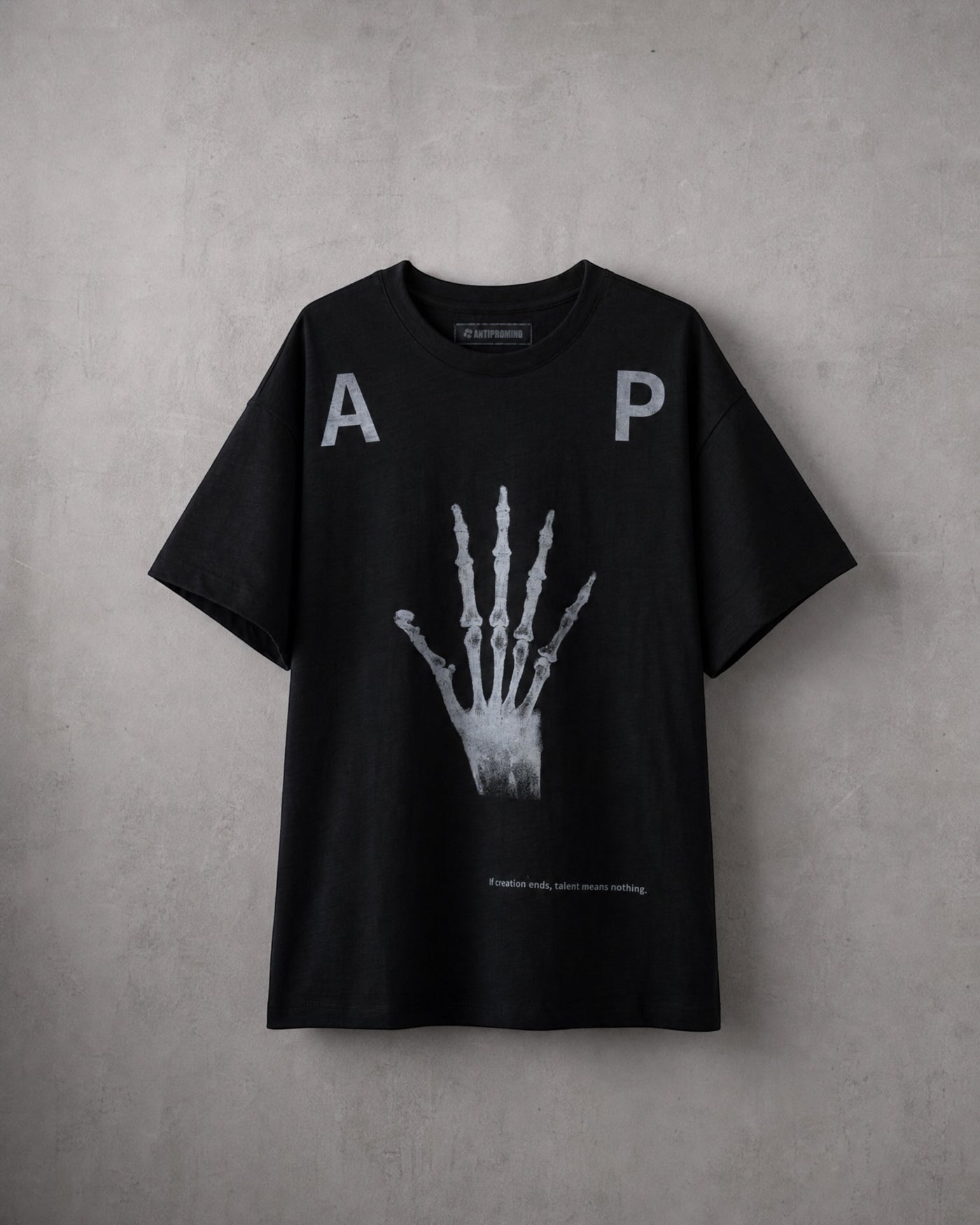 ANTIPROMINDの黒い天竺コットンTシャツ。フロントにスケルトンハンドのグラフィックとタイポグラフィがプリントされたリラックスフィットの半袖シャツ。