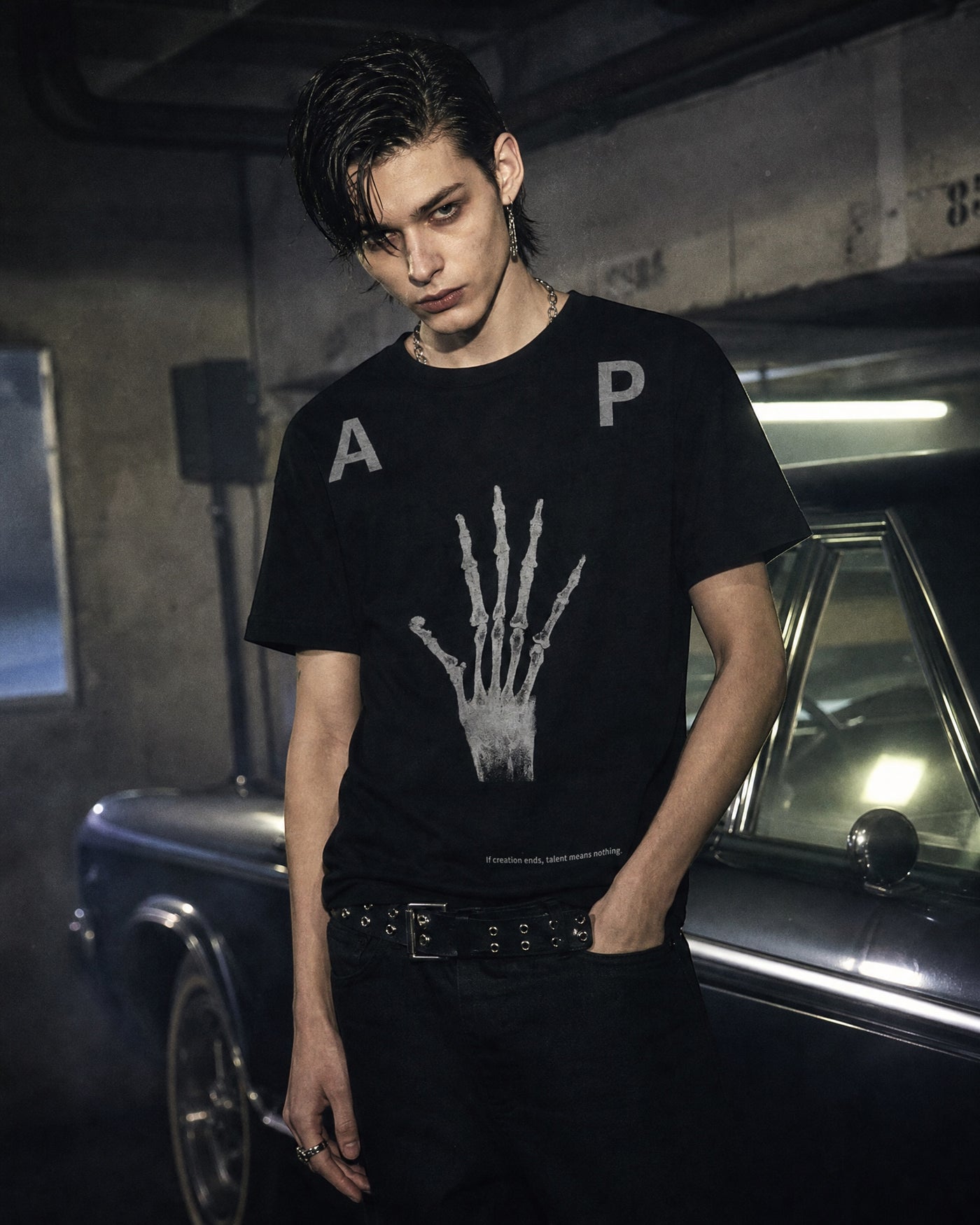 ANTIPROMINDの黒い天竺コットンTシャツ。スケルトンハンドのグラフィックとヴィンテージ調のプリントが特徴のリラックスフィット。