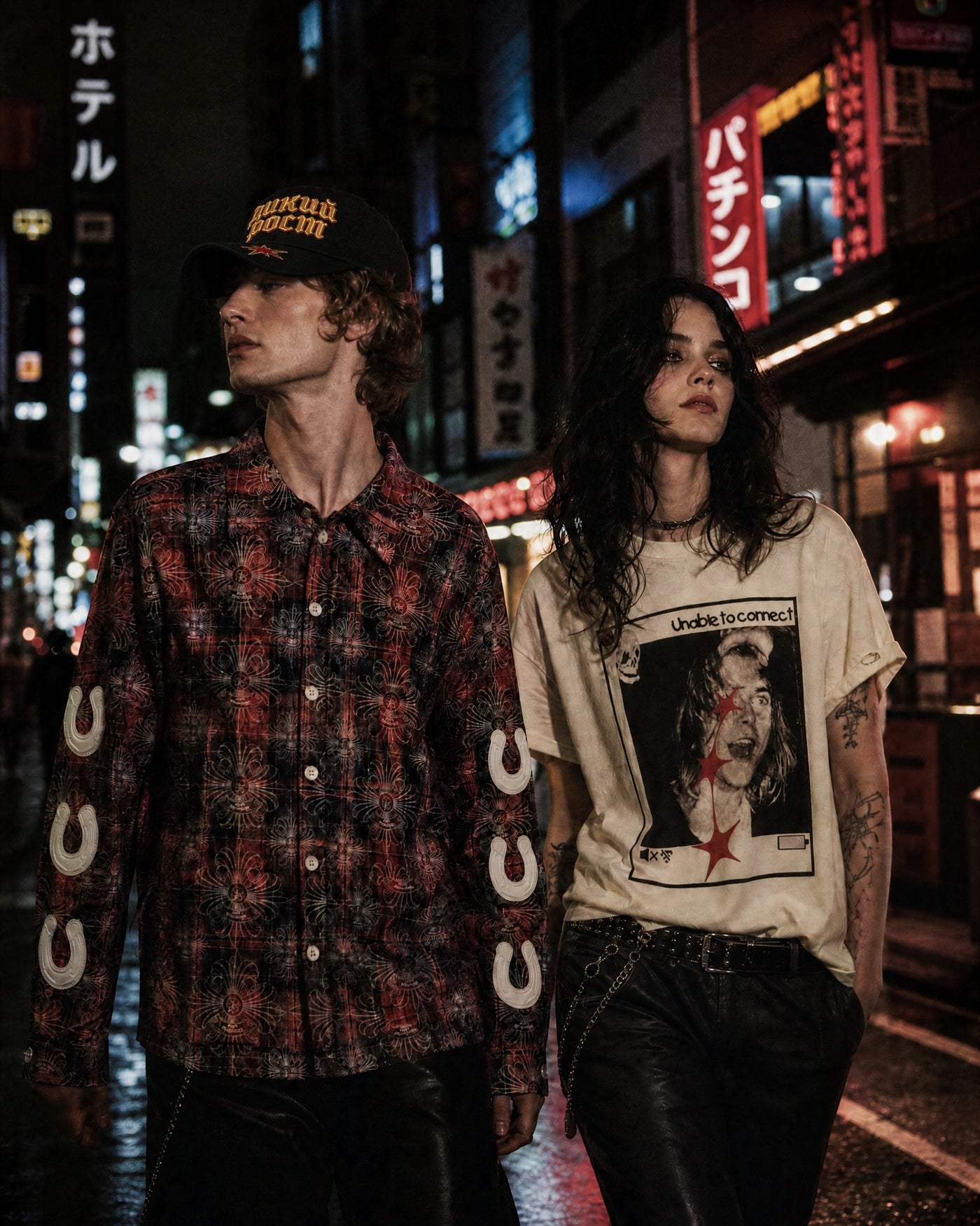 ANTIPROMINDの赤系チェック柄シャツ。クロスとクローバーの総柄プリントと袖のホースシューパーツが特徴のコットン製ショート丈シャツを着用した男性モデル。