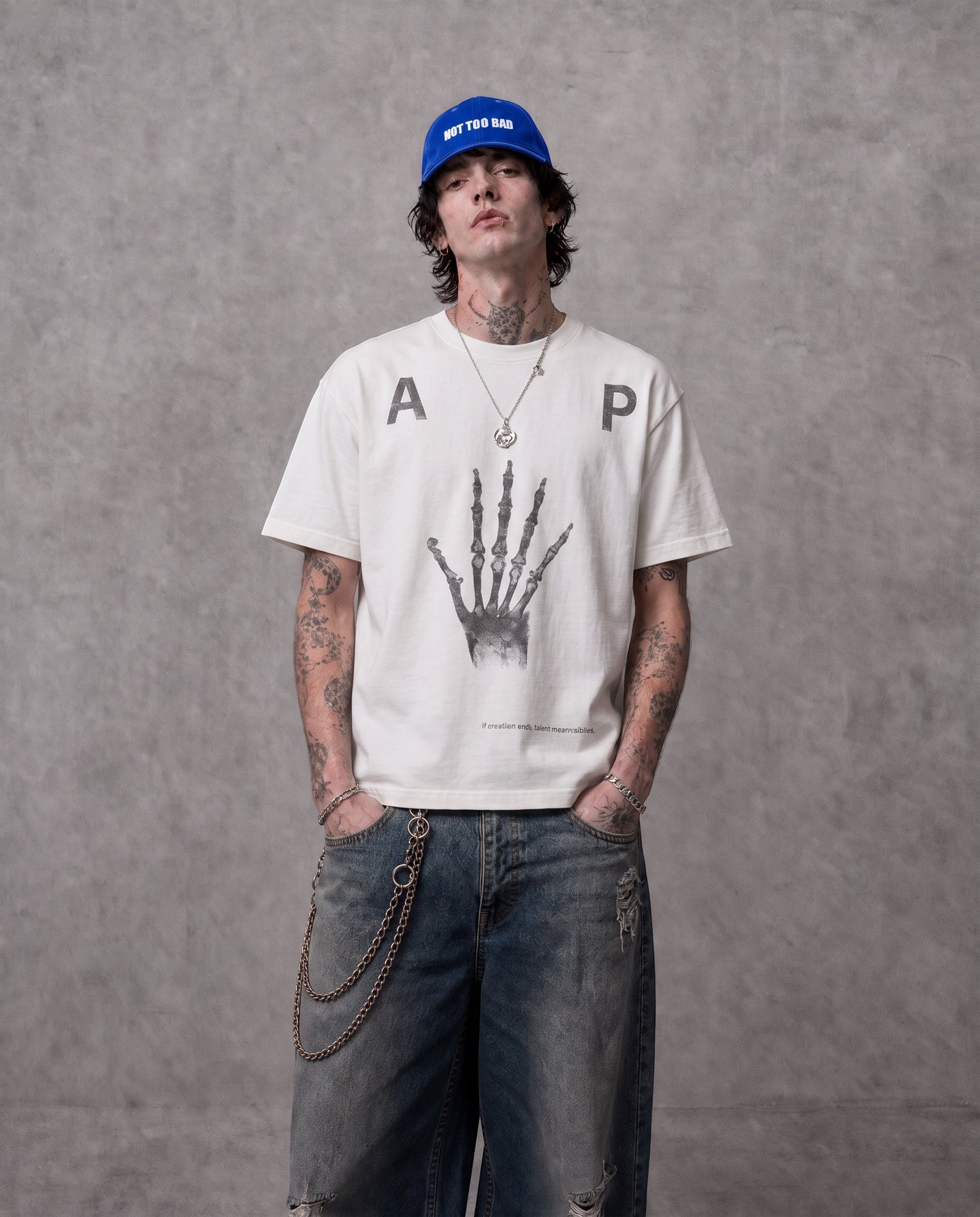 ANTIPROMINDのスケルトンハンドグラフィックがプリントされたホワイトの天竺コットンTシャツを着用した男性モデル