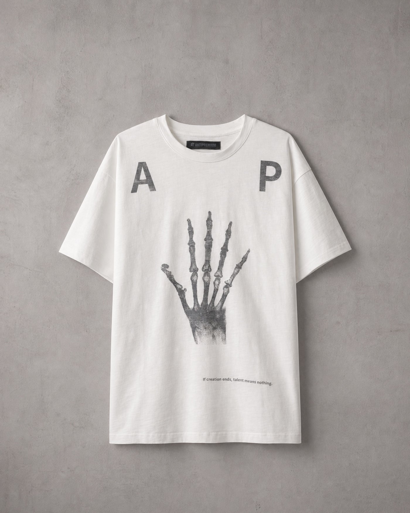 ANTIPROMINDのホワイト天竺コットンTシャツ。フロントにスケルトンハンドのグラフィックとタイポグラフィがプリントされたリラックスフィットの半袖シャツ。